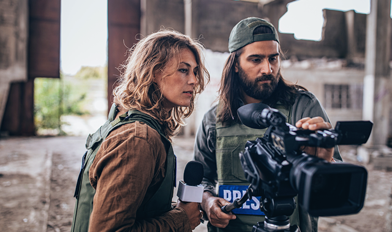 Photo of a press team of a journalist and cameraman on field