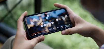 Photo of hands holding a mobile phone with video playing on it