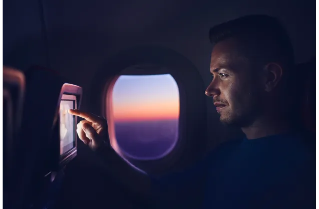 Photo of a passenger watching a film on a play with an evening skylight outside