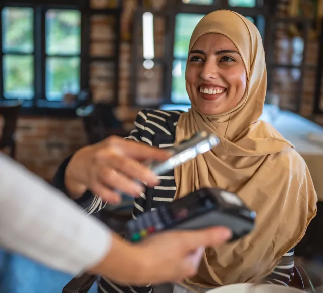 Photo of a woman using her mobile for payment in a store