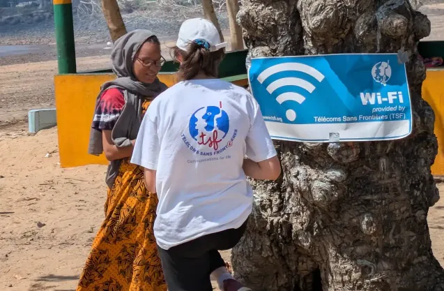 Photo of two women standing in an African Rural landscape using a Wifi hotspot