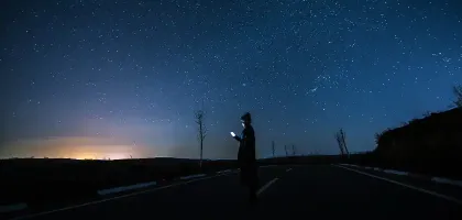 Woman using a smart phone under starry sky at Night