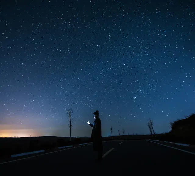 Woman using a smart phone under starry sky at Night