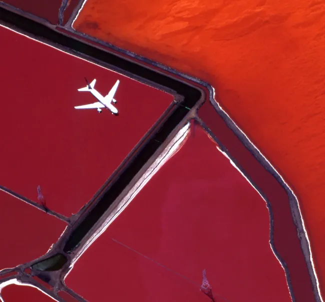 Aerial photo of a white plane flying above a red landscape
