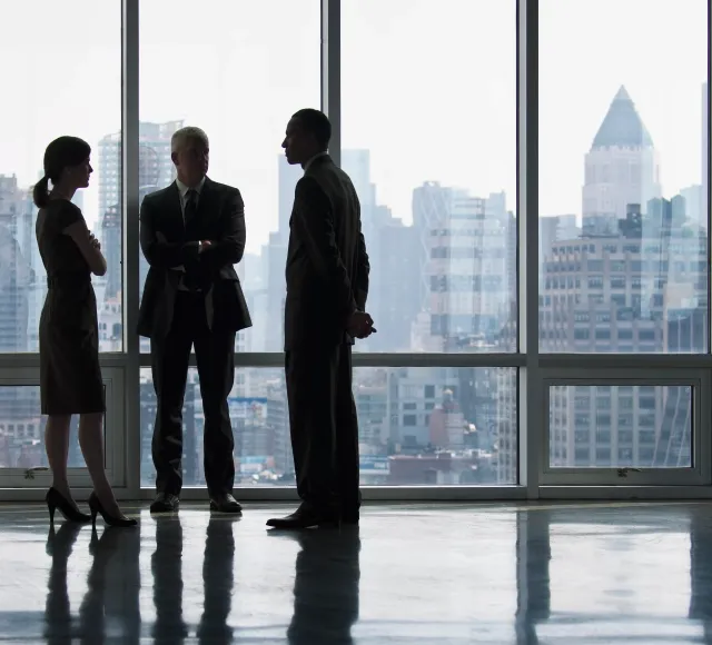 Photo of corporate office with 3 people standing and talking