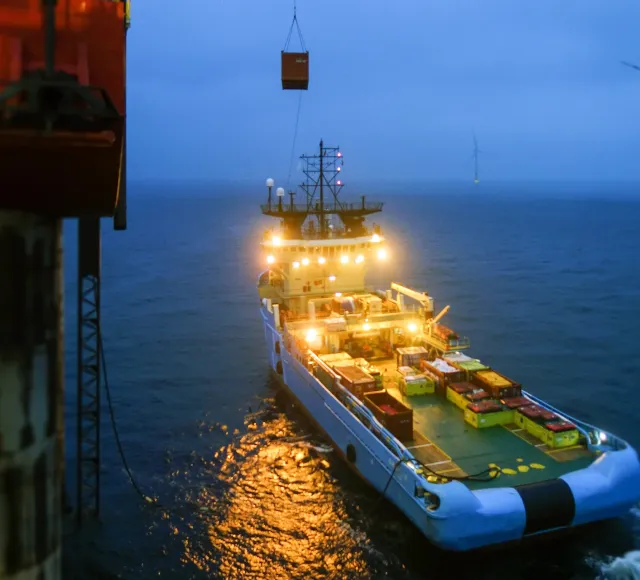 Photo of a boat shot from an offshore rig during sunset