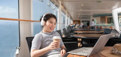 Photo of a woman using her laptop while travelling on a cruise ship
