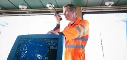 Ships worker on bridge using walkie-talkie