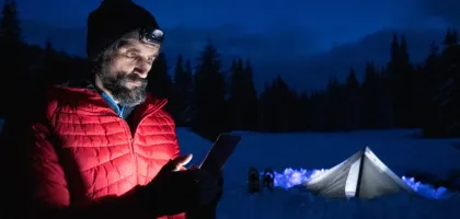 Photo of a man using a tablet while camping during winter