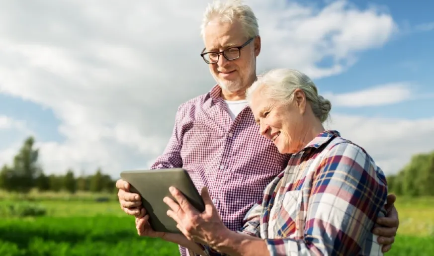 Photo of an elderly couple looking at their mobile phone outdoors