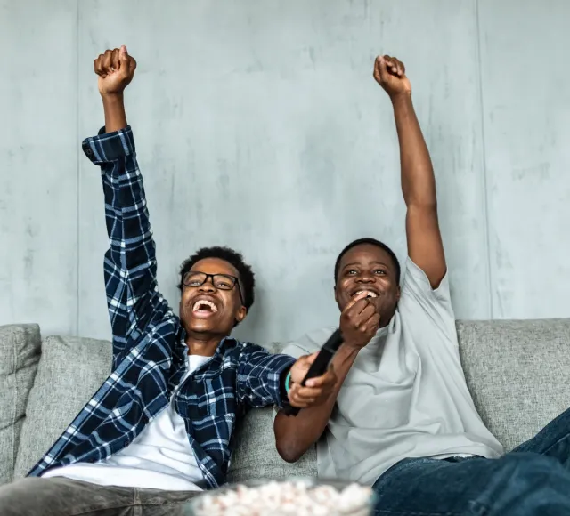 Photo of friends watching TV and cheering for their team