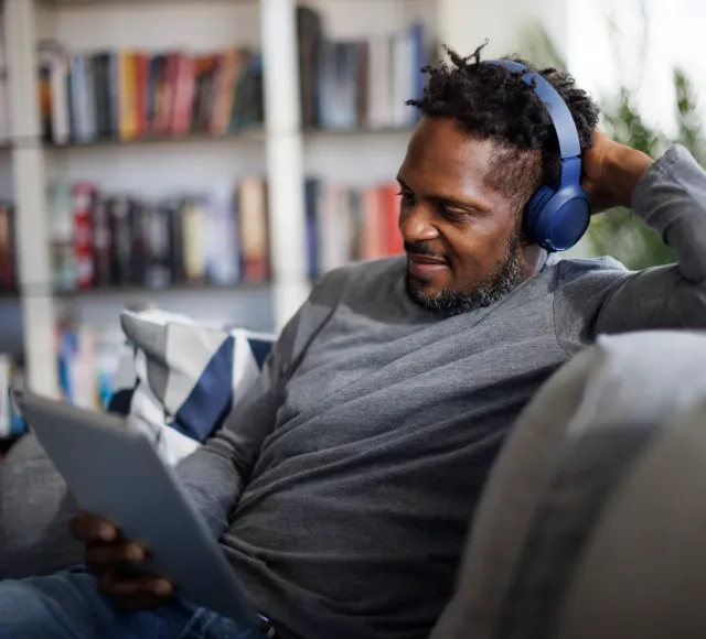 Photo of a man using a tablet with headphones