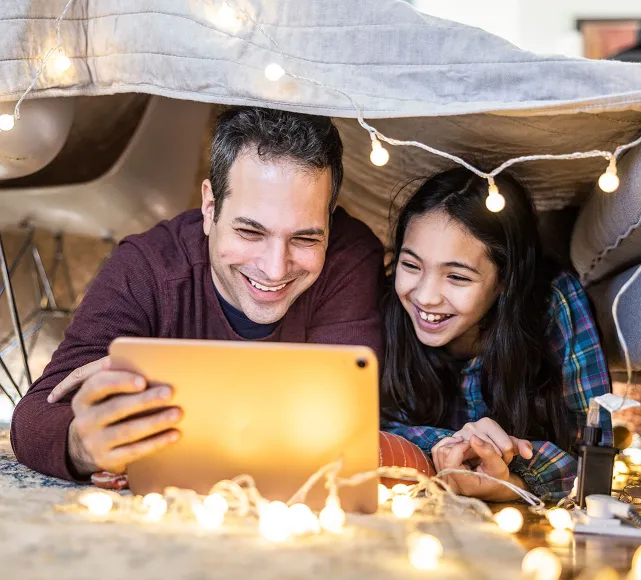 Photo of a dad and daughter watching tablet