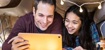 Photo of a dad and daughter watching tablet