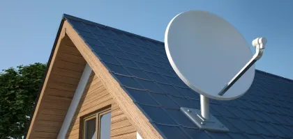 Roof of wooden house in rural location with satellite dish