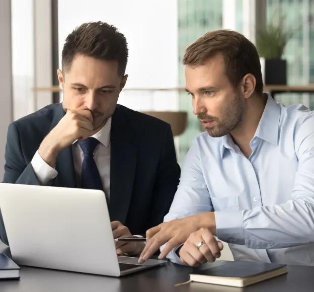 Photo of two business men viewing a laptop